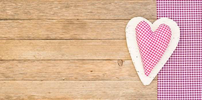 Pink fabric heart on wooden background with copy space