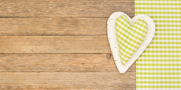 Green fabric heart on wooden background with copy space