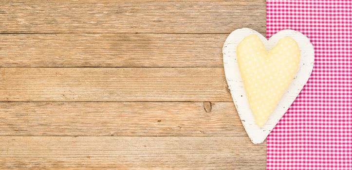 Rustic yellow fabric heart on wooden background with copy space