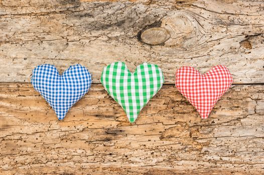 Rustic hearts in blue, green and red on vintage wooden background with copy space