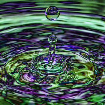 Water splash, droplet with a multi coloured blue green iridescent transparent ripple splash 