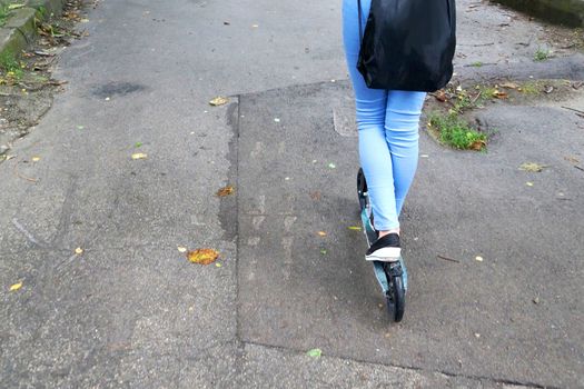 girl with a backpack rides a scooter in the park, copy space