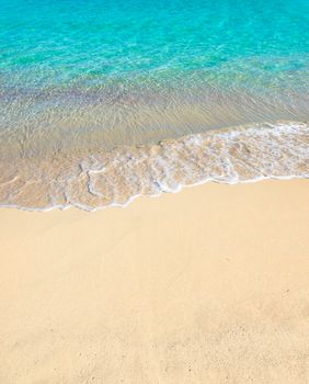Close-up of sandy beach with soft sea water wave, background texture