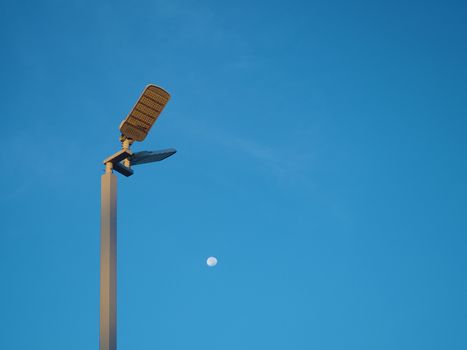 The spotlight tower on the background is a blue sky And there is a small moon in the middle.
Energy and nature concepts.
Minimal image.