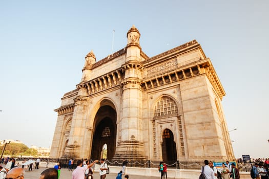 Mumbai, India - 9 November: The Gateway of India with tourists and sellers on a clear autumn evening