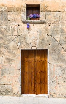 Detail view of mediterranean house with rustic wooden door and window with flower decoration