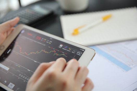 Woman hand Trading online on tablet with business paper and coffee