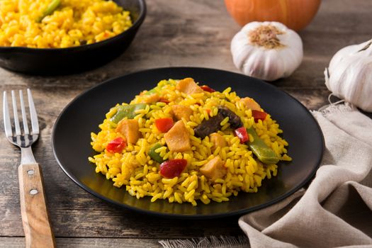 Fried rice with chicken and vegetables on black plate on wooden table