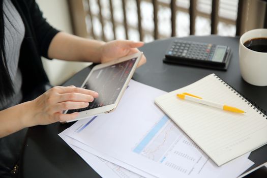 Woman hand Trading online on tablet with business paper and coffee