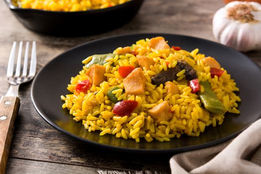 Fried rice with chicken and vegetables on black plate on wooden table