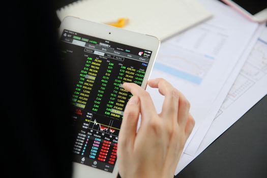 Woman hand Trading online on tablet with business paper and coffee