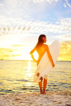 Surfing surfer girl looking at ocean beach sunset. Female bikini woman looking at water with standing with surfboard living healthy active lifestyle. Surf model on Oahu, Hawaii, USA.