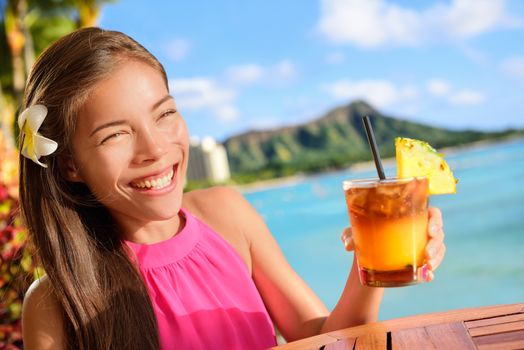 Beach bar party drinking friends toasting Hawaiian sunset cocktails having fun. Asian woman looking at camera holding alcoholic drink cheering in Waikiki beach, Honolulu city, Oahu, Hawaii USA.