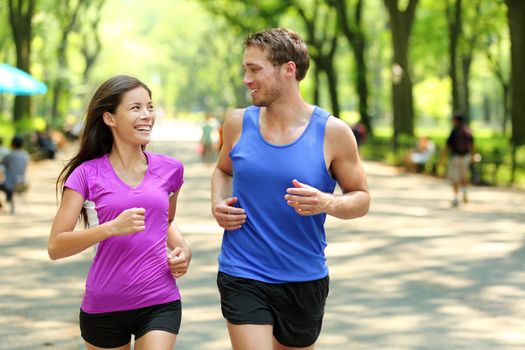 Running couple training in Central Park, New York City (NYC). Happy runners talking together during run on famous Mall walk path under trees in Manhattan, urban fitness.