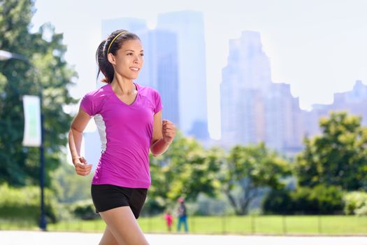 Run woman exercising in Central Park New York City with urban background of skyscrapers skyline. Active Asian female runner running with purple t-shirt and shorts sportswear.