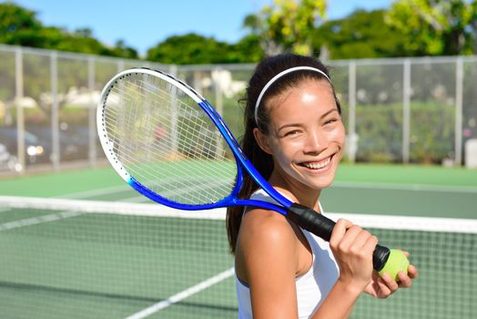 Portrait of female tennis player holding tennis racket after playing at game outside on hard court in summer. Fit woman sport fitness athlete smiling happy living healthy active lifestyle outside.