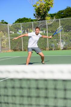 Tennis player - man hitting forehand playing outside on hard court. Male sport fitness athlete practicing in summer outdoors living healthy active lifestyle.