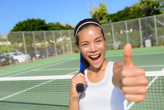 Tennis player woman giving thumbs up happy and excited looking at camera. Successful winning female athlete living healthy active sport fitness lifestyle outdoors in summer on tennis court.