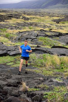 Trail Running fitness male ultra runner in nature landscape, volcanic rocks. Sport running man in cross country trail run. Male athlete exercising and training in summer outdoors.