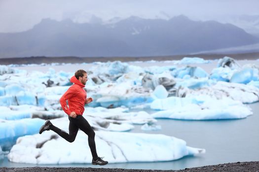 Running man. Sprinting trail runner in fast sprint in beautiful nature landscape. Fit male athlete sprinter cross country running by icebergs in Jokulsarlon glacial lake in Iceland.