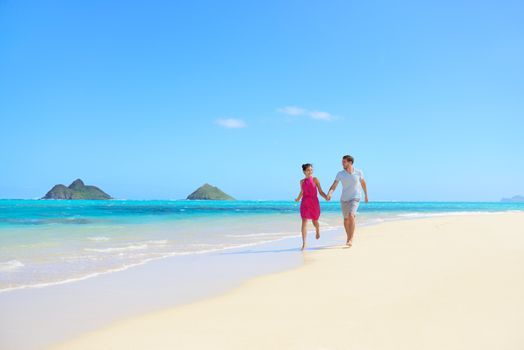 Beach couple happy having fun on Hawaii honeymoon. Romantic couple cheerful and full of happiness on travel vacation on Lanikai beach, Oahu, Hawaii, USA with Mokulua Islands. Asian woman, Caucasian man