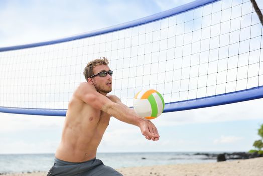 Beach volleyball man playing game hitting forearm pass volley ball during match on summer beach. Male model living healthy active lifestyle doing sport on beach.