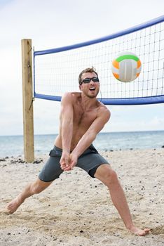 Man playing beach volleyball game hitting forearm pass volley ball on summer beach. Male model living healthy active lifestyle doing sport on beach wearing sunglasses