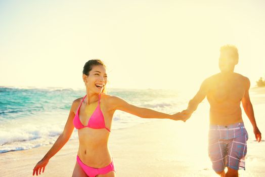 Laughing happy romantic couple summer vacation beach fun. Joyful multi-ethnic young couple laughing elated together on tropical beach holiday on resort. Mixed race Asian woman and Caucasian man.