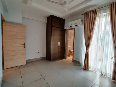 Wide angle shot of bedroom with airconditioner and colorful curtains. Shot at a modern expensive beautifully maintained flat or apartment in Delhi, Gurgaon, Noida for premium individuals. Shows the real estate of India