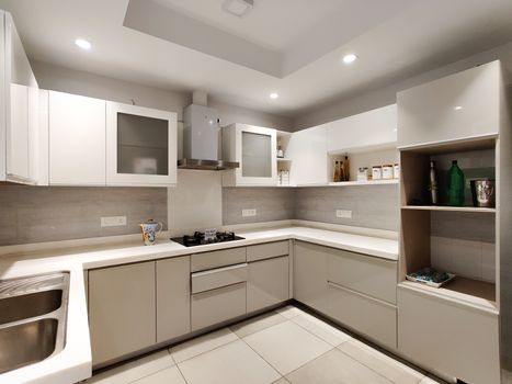Wide angle shot of a modern modular kitchen with inset lights and cabinets. Shot at a modern expensive beautifully maintained flat or apartment in Delhi, Gurgaon, Noida for premium individuals. Shows the real estate of India