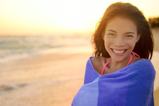 Bathing beach woman with towel happy portrait. Young pretty mixed race Asian Caucasian girl wrapped in towel standing in beach sunset. Smiling happy enjoying summer holiday travel vacation. Hawaii.