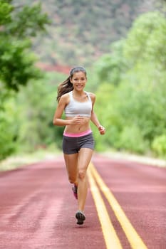 Runner woman running training living healthy fitness sport lifestyle. Active female athlete jogging outdoors happy with aspirations. Beautiful mixed race Asian Caucasian girl in full body length.