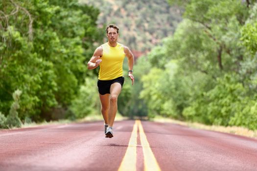 Running man runner sprinting for fitness and health. Male athlete in sprint run wearing sports running shoes and shorts in workout for marathon. Full body length view sprinter running towards camera.