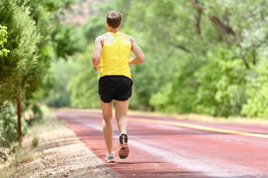 Running man runner jogging for fitness and health. Male athlete on working out on run wearing sports running shoes and shorts in workout for marathon. Full body length view showing back running away.