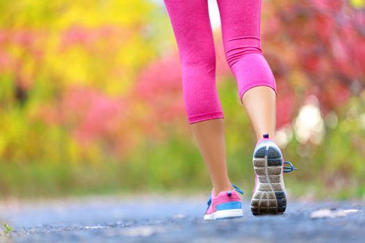 Jogging and running woman with athletic legs on jog or run on trail in forest in healthy lifestyle concept with close up on running shoes. Female athlete jogging and training outdoors in autumn fall.