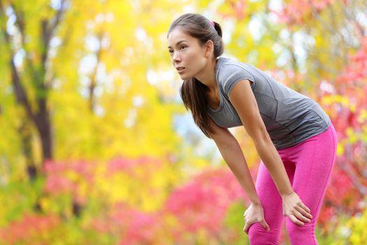 Athlete runner resting after running - Asian woman. and jogging training outdoors in forest. Tired exhausted beautiful sports fitness model living healthy active lifestyle. Mixed race Asian Caucasian.