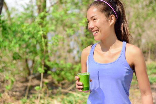 Green detox smoothie - woman drinking vegetable smoothie after fitness running workout on summer day. Fitness and healthy lifestyle concept with beautiful fit mixed race Asian Caucasian model.