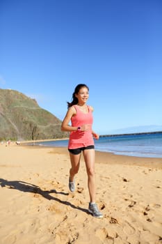 Runner sports athlete running woman on beach sweating and jogging. Fit exercising female fitness model working out training for marathon run. Biracial Asian Caucasian sports girl.