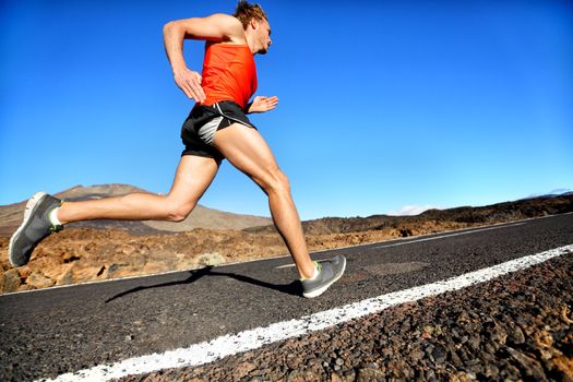 Runner man running sprinting for success on run. Male athlete runner training at fast speed. Muscular fit sport model sprinter exercising sprint on mountain road. Full body length of Caucasian model.