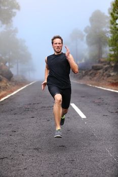 Healthy running runner man workout on mountain road. Jogging male fitness model working out training for marathon on forest road in amazing nature landscape.