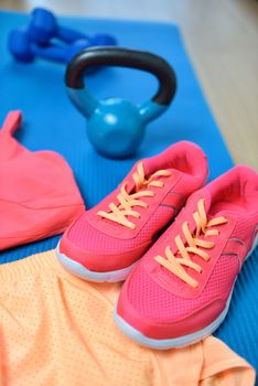 Gym shoes - Fitness outfit closeup with kettlebell. Crossfit workout clothes on yoga mat in pink neon color with weights in the background on the floor. Fashion activewear clothes concept.