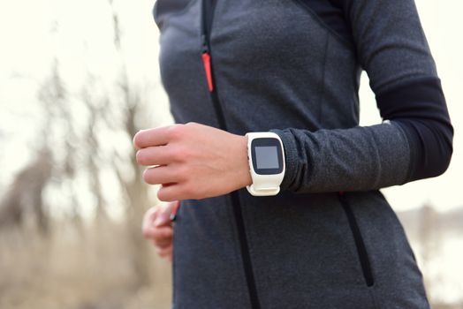 Smartwatch woman running with heart rate monitor. Closeup of female wrist wearing smart sport watch as activity tracker outdoors during cardio workout.