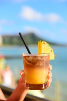 Mai Tai hawaiian drink on beach bar. Close up of alcoholic drink. Friends toasting having fun on Waikiki beach, Honolulu city, Oahu, Hawaii USA.