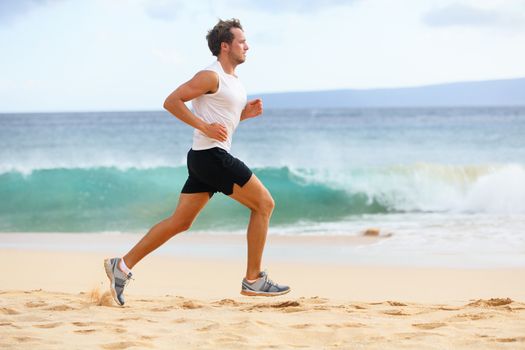 Fitness sports runner man jogging on beach. Handsome young fit sporty male athlete running outside on beautiful beach training. Caucasian male model in his 20s working out in full body length.