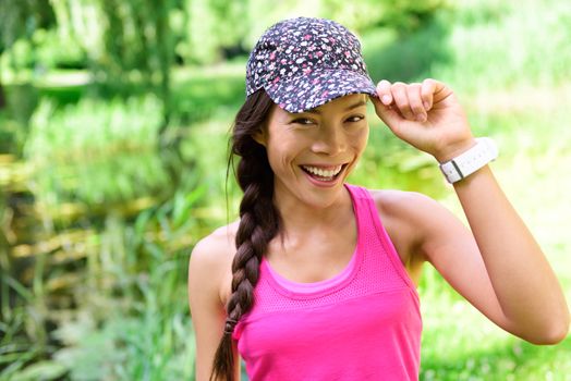 Portrait of woman runner wearing running cap. Female athlete smiling happy at camera after jogging in city park wearing floral headwear hat.