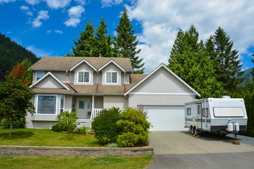 Big residential house with RV trailer parked on driveway. Family house on country side in British Columbia, Canada