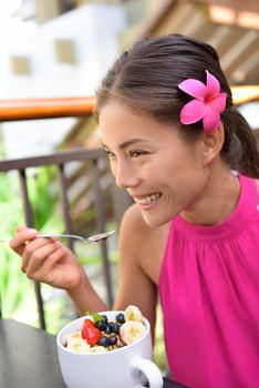 Acai bowl - girl eating healthy food outdoors. Woman enjoying acai bowls made from acai berries and fruits outdoors for breakfast.