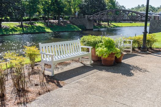 White park benches along side a river bank