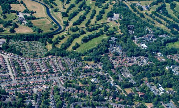 Aerial shot from a plane window of the English countryside showing town houses and part of a gold course