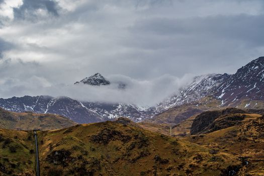 Peak of Mount Snowdon in Wales UK partially covered by cloud and snow